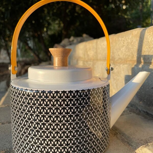 alt="black tea pot with designs"